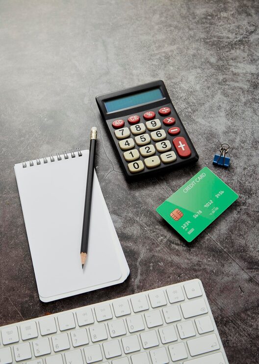 Calculator, credit card, notebook and pencil on desk — tools to help you learn how to pay off debt fast