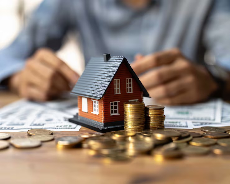 How to calculate mortgage payments - model house with stacked coins and cash representing monthly mortgage payment calculation