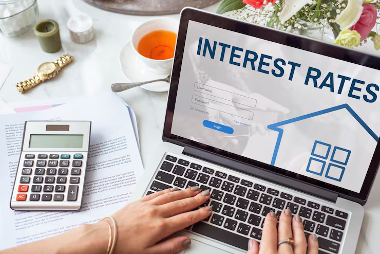 Comparing APR vs interest rate on laptop mortgage login screen with calculator and documents