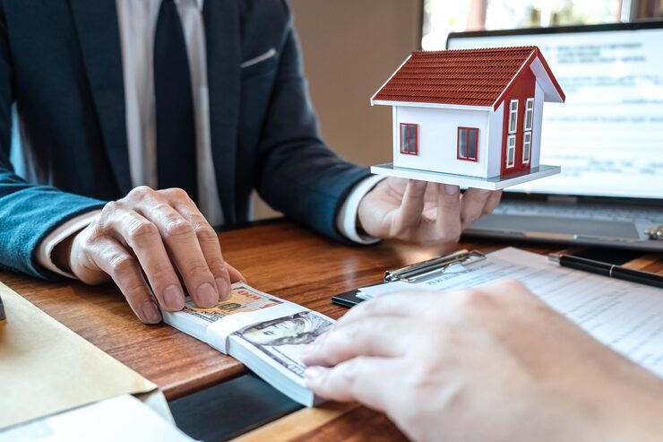 mortgage refinancing explained loan officer holding house model with cash