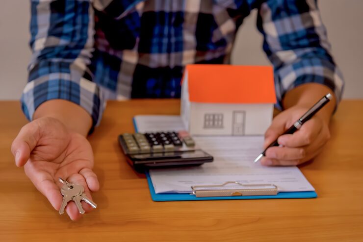 What determines mortgage rates - person signing home loan documents with house model and calculator